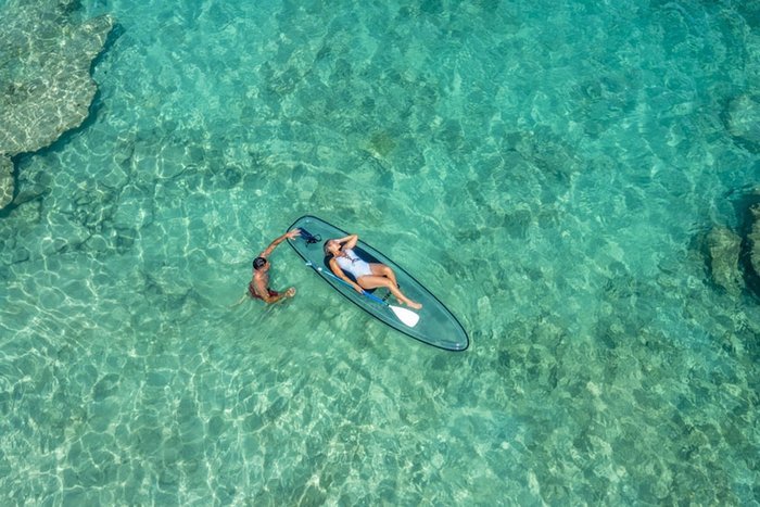 A paddleboarder gliding on crystal-clear water at Galley Bay Resort & Spa