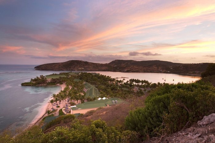 Palm trees silhouetted against a sunset beach at St. James's Club & Villas Antigua
