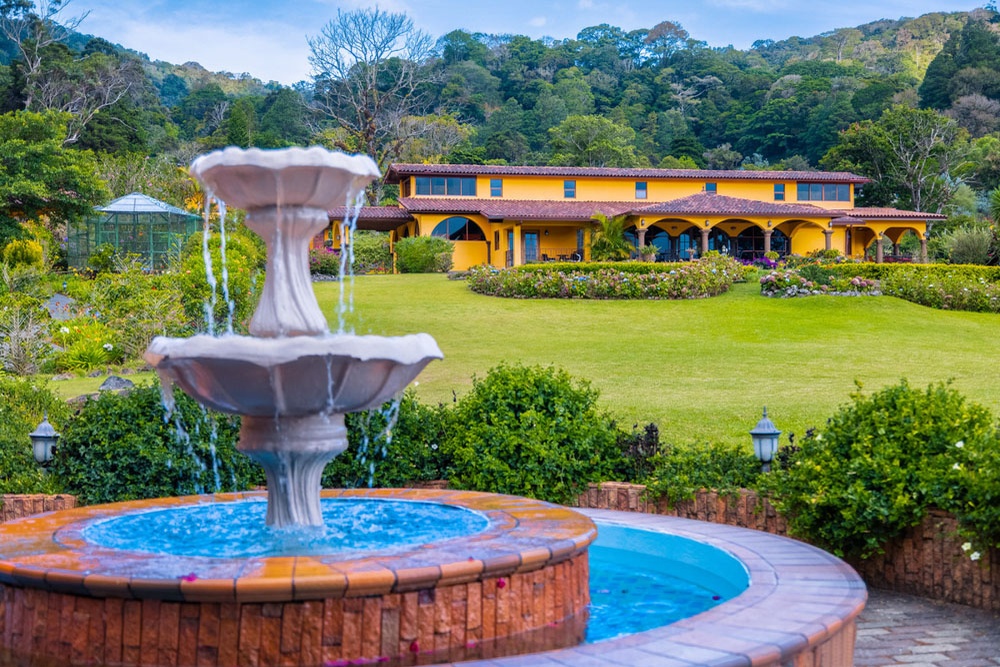 The garden fountain and yellow hacienda of Los Establos Boutique Resort Panama, framed by Boquete's lush mountains