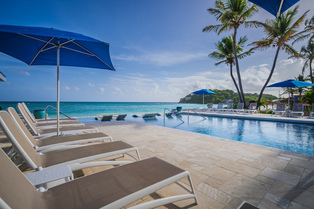 Infinity pool framed by palm trees with the Caribbean beyond at Pineapple Beach Club Antigua