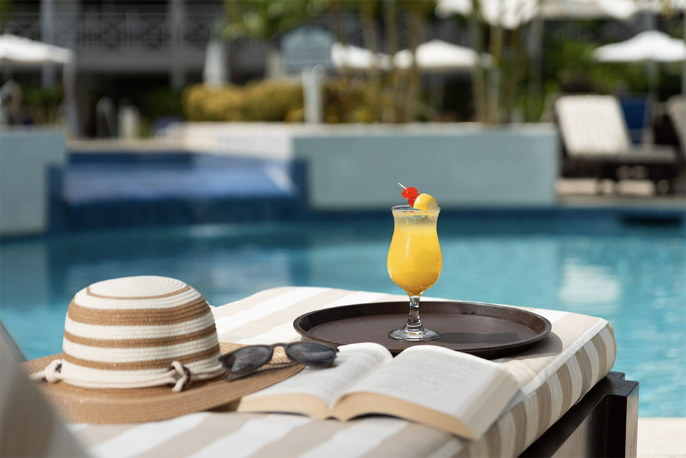 Friends sharing drinks on lounge chairs by the sea at The Club Barbados